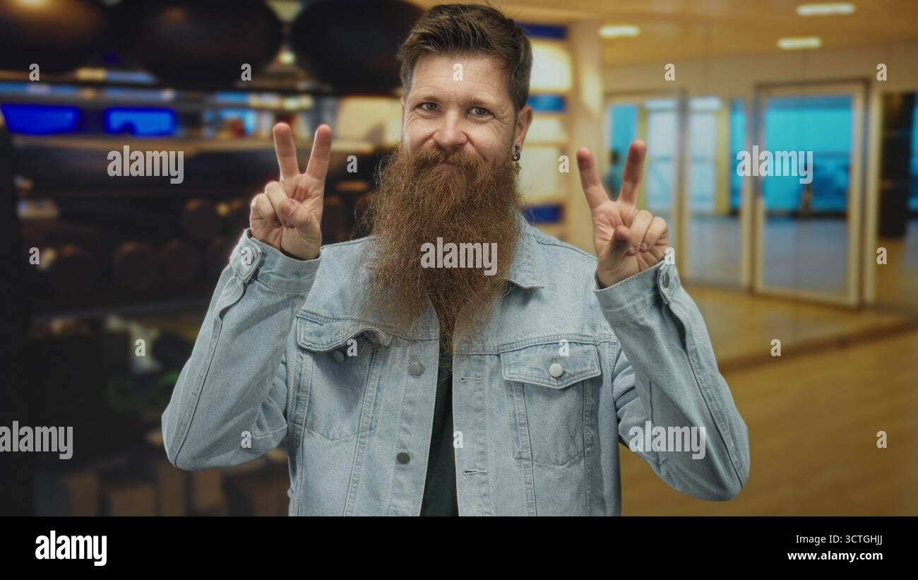 Junger Mann, der Zitate im Fitnessraum in einem Fitnessgebäude mit Gewichthängen und Übungsbälle macht; Ironie. Stockfoto