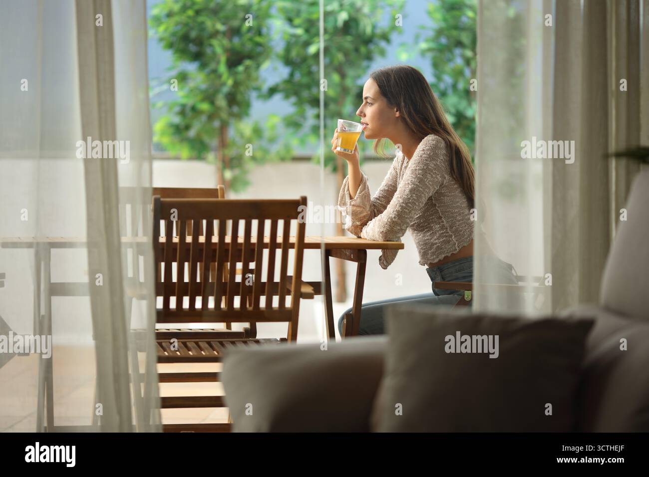 Profil einer Teetrinkenden Frau, die auf einer Terrasse in einem Haus sitzt Stockfoto