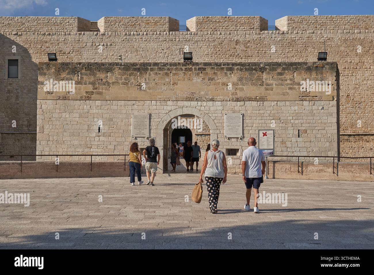 Besucher gehen in Richtung des Eingangs einer alten Steinburg, einer historischen Festung und einer Touristenattraktion in Europa Stockfoto