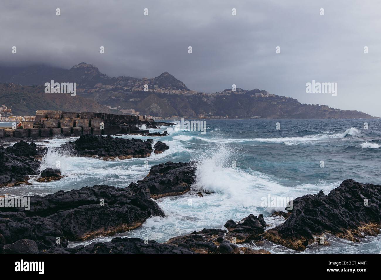 Blick von der Küste in Giardini Naxos in der Metropolstadt Messina auf der Insel Sizilien, Italien. Taormina Stadt und Castelmola Stadt im Hintergrund Stockfoto