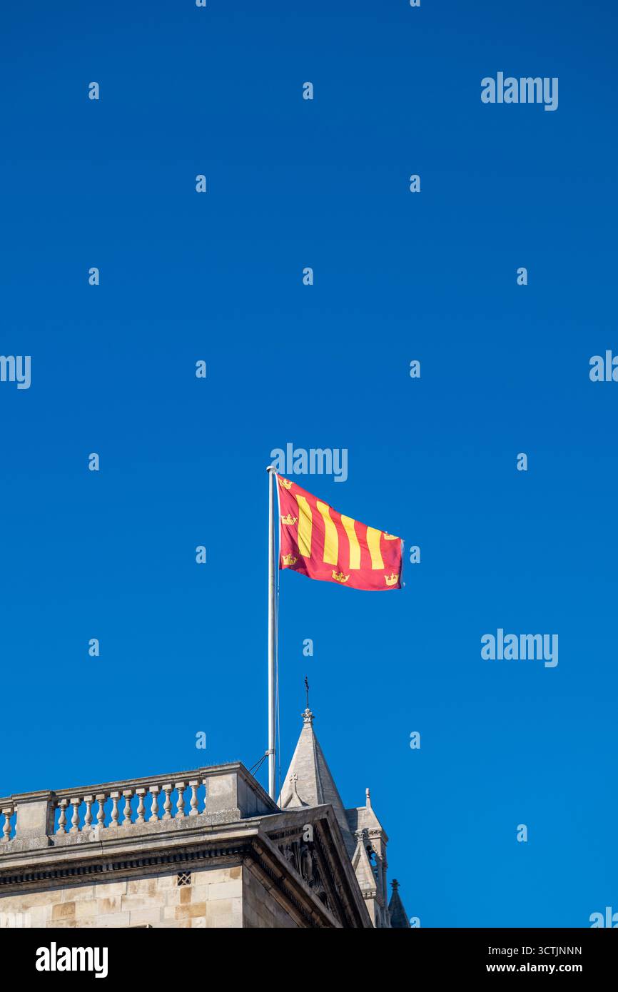 Flagge des Peterhouse College, University of Cambridge, über dem historischen College-Gebäude vor einem klaren blauen Himmel, Cambridgeshire, England Stockfoto