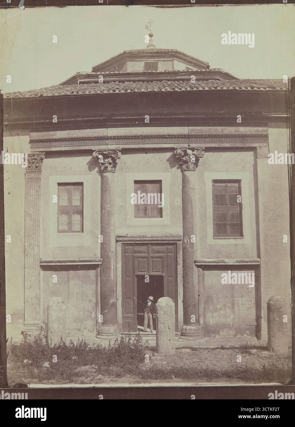 Kirche in Italien, 1870-1880. Es hat eine geradlinige Struktur, dreiachsige fa&#xe7;ade mit zwei eingebetteten Spalten. Dieser Effekt wurde höchstwahrscheinlich durch das Mauern eines viel älteren Portikus verursacht, so dass es sich wahrscheinlich um ein umgestaltetes altes Gebäude handelt. Die Kapitelle der Säulen repräsentieren die römische Varietät der korinthischen Ordnung – sie stützen eine niedrige Entablature mit einem Architrave und einem Cymatium, das mit einem Ochsenaugenornament verziert ist (oben beschattet). Am linken Rand der fa&#xe7;Ade befindet sich ein Eckpfeiler (so genannte anta) mit geriffeltem Schaft, der rechts kein Äquivalent hat (wobei nur Stockfoto