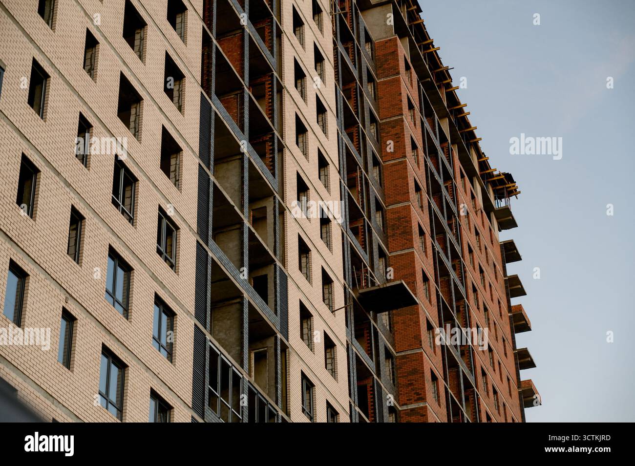 Ein mehrstöckiges Wohngebäude aus rotem Backstein und Beton im Bau. Unvollendete Konstruktion eines Hochhauses mit Ziegelverkleidung Stockfoto