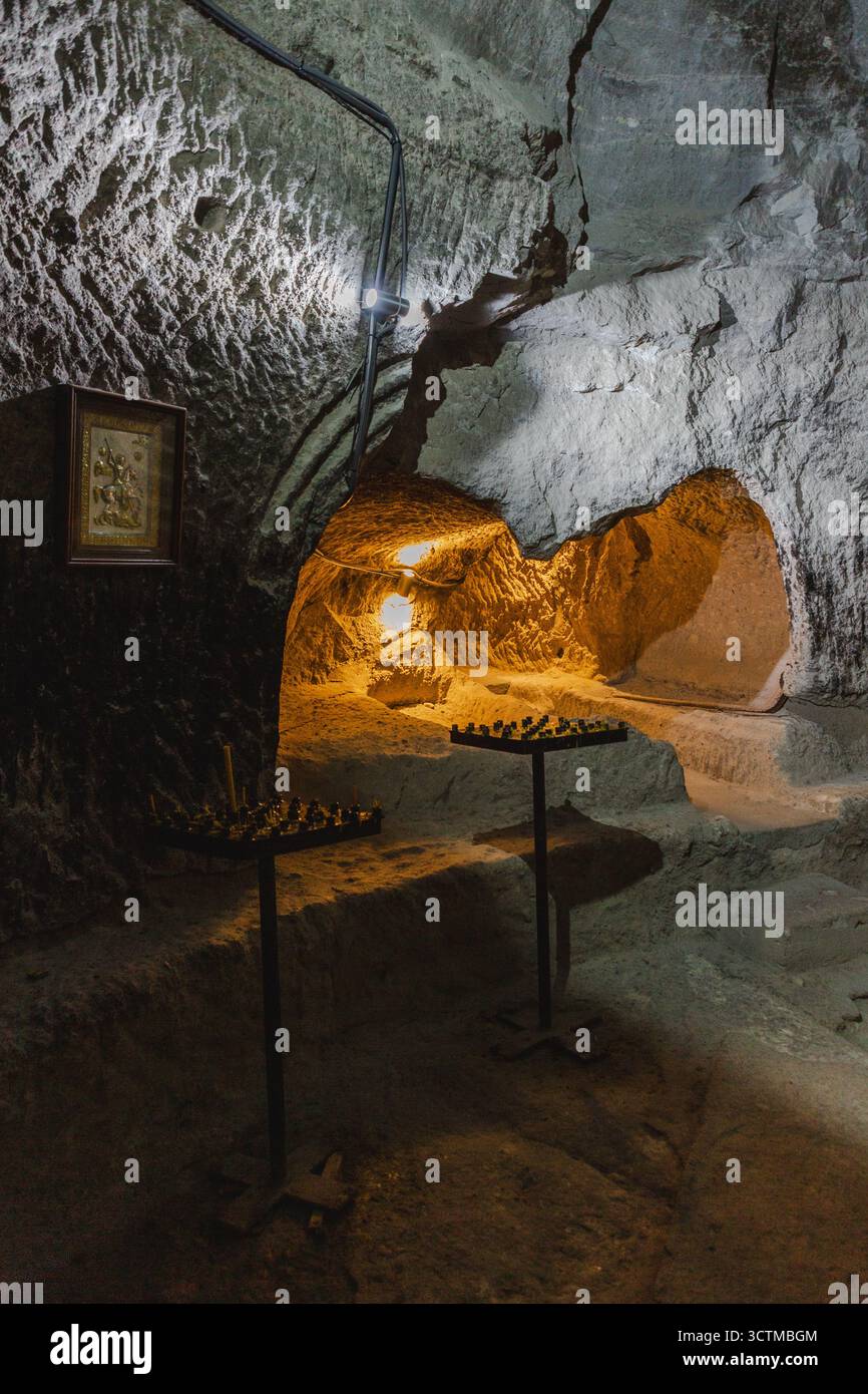 Blick auf die innere Höhle mit Kerzen und Licht, die die dunklen Steinmauern beleuchten und eine warme und einladende Atmosphäre schaffen, Vardzia, Imereti, Georgia. Stockfoto