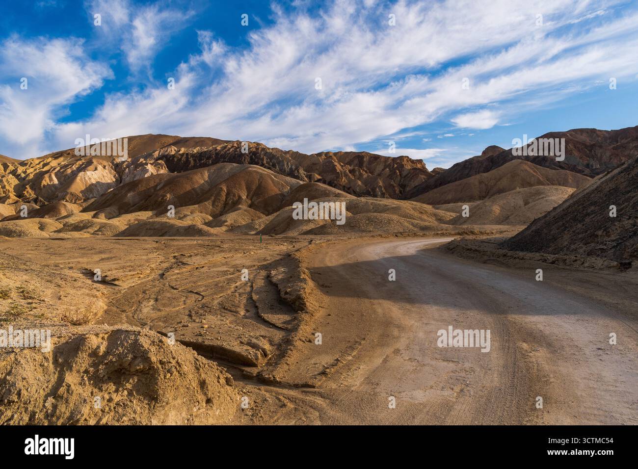 Helle, skulpturierte Hügel und gewundene Straße im 20er Mule Team Canyon mit dramatischer Erosion unter blauem Himmel. Stockfoto