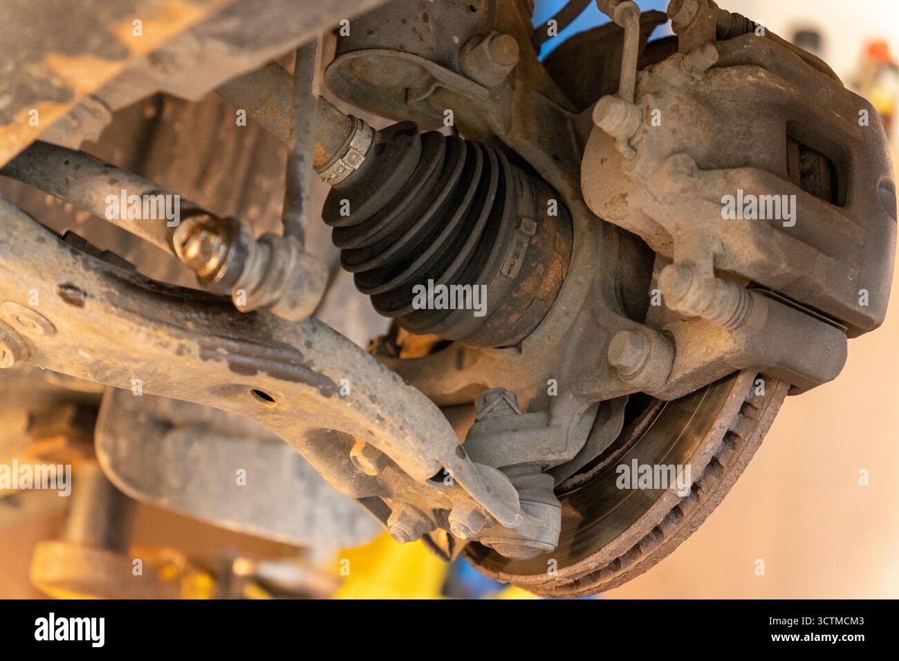Nahaufnahme einer Vorderradnabe mit Bremsmechanismus, Aufhängungsarmen, Antriebswelle und Gleichlaufgelenk in einer Gummimanschette. Autoreparaturkonzept. Stockfoto