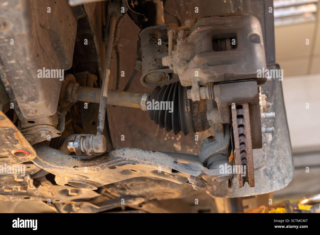 Nahaufnahme einer Vorderradnabe mit Bremsmechanismus, Aufhängungsarmen, Antriebswelle und Gleichlaufgelenk in einer Gummimanschette. Autoreparaturkonzept. Stockfoto