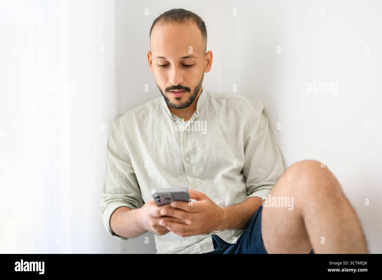 Junger islamischer araber, der zu Hause das Handy benutzt Stockfoto