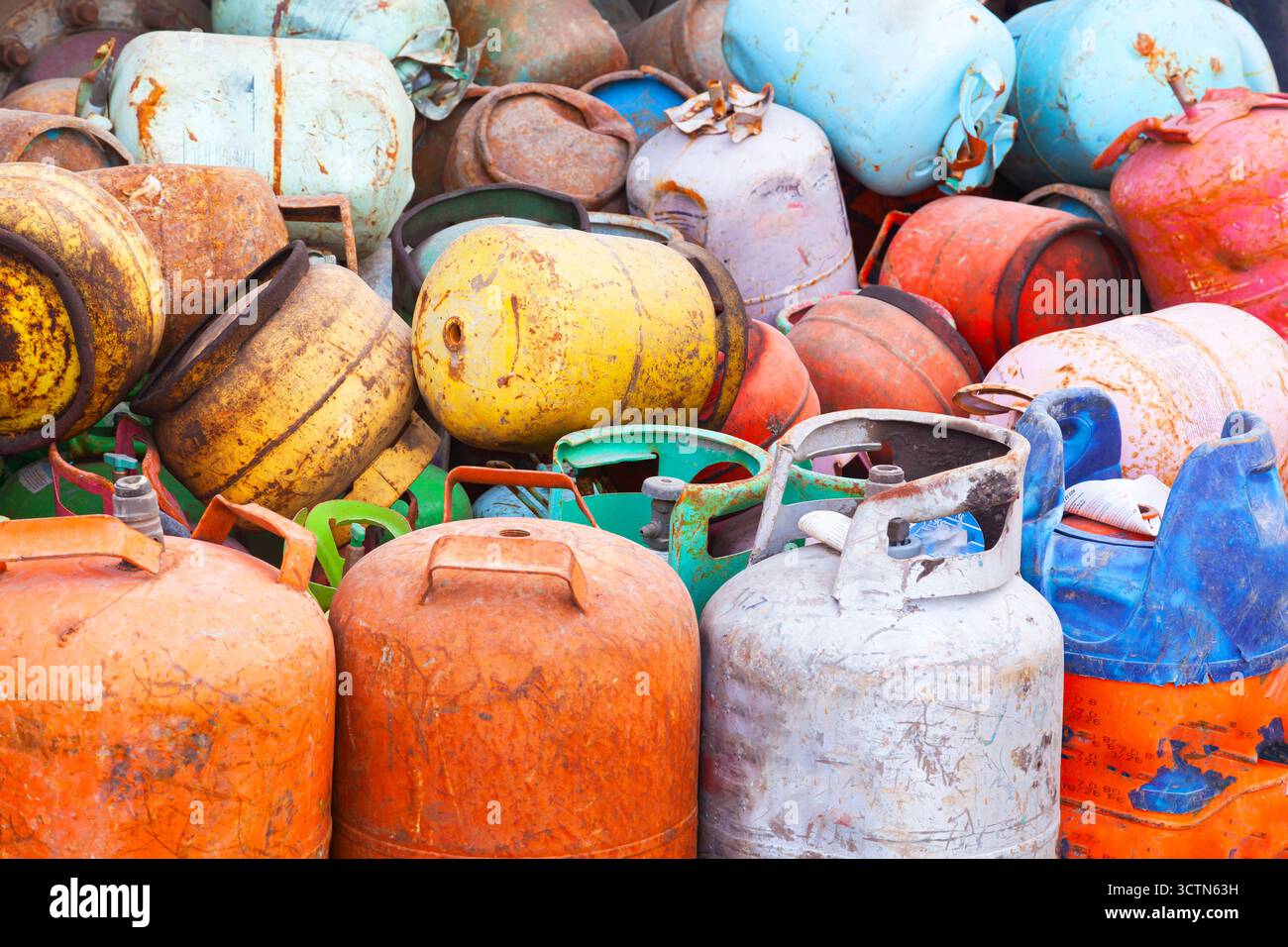 Ein Haufen alter gebrauchter, mehrfarbiger Gasflaschen kleiner Größe. Metallschrott aus Gasflaschen. Stockfoto