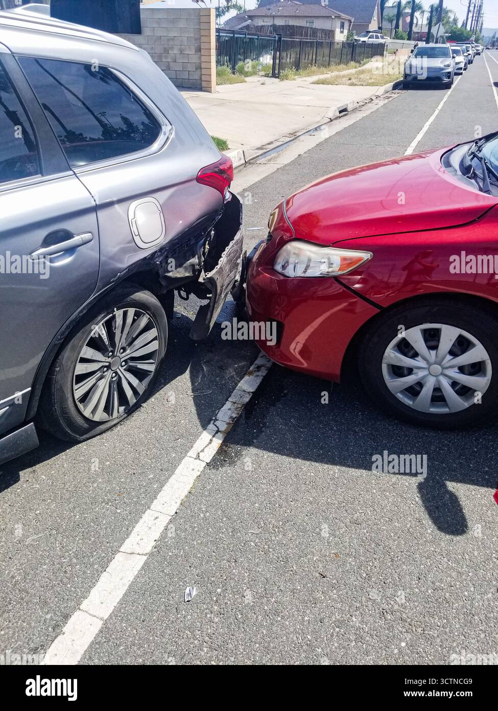 Ein rotes Auto und ein silberner SUV stoßen auf einer Stadtstraße auf, wodurch beide Fahrzeuge beschädigt werden. Stockfoto