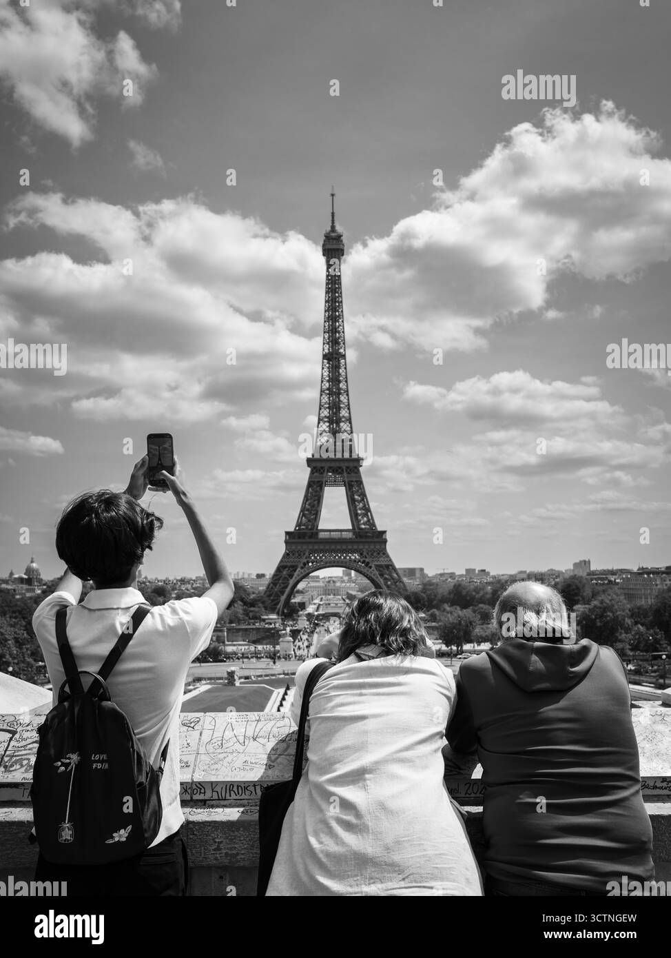 Touristen sehen und fotografieren den Eiffelturm von einem Pariser Aussichtspunkt in Schwarz-weiß. Stockfoto