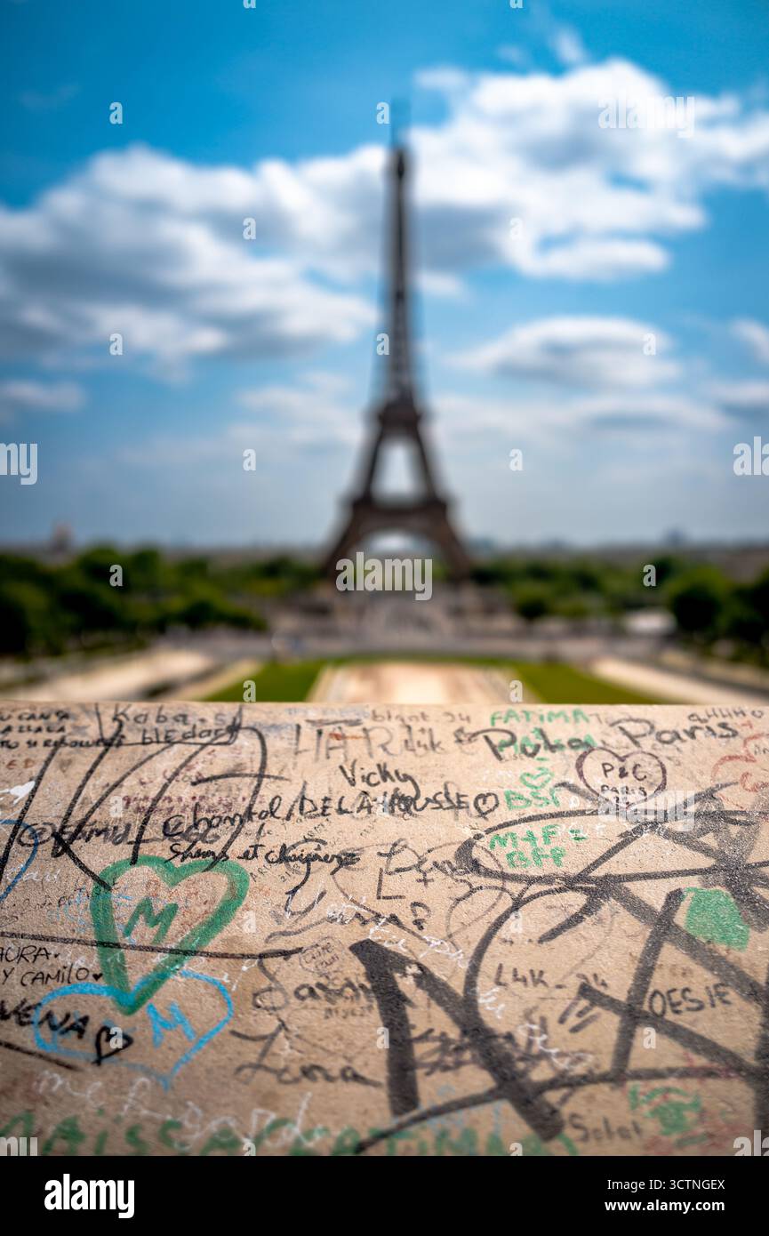 Graffiti im Vordergrund mit verschwommenem Eiffelturm im Hintergrund unter hellem Himmel. Stockfoto