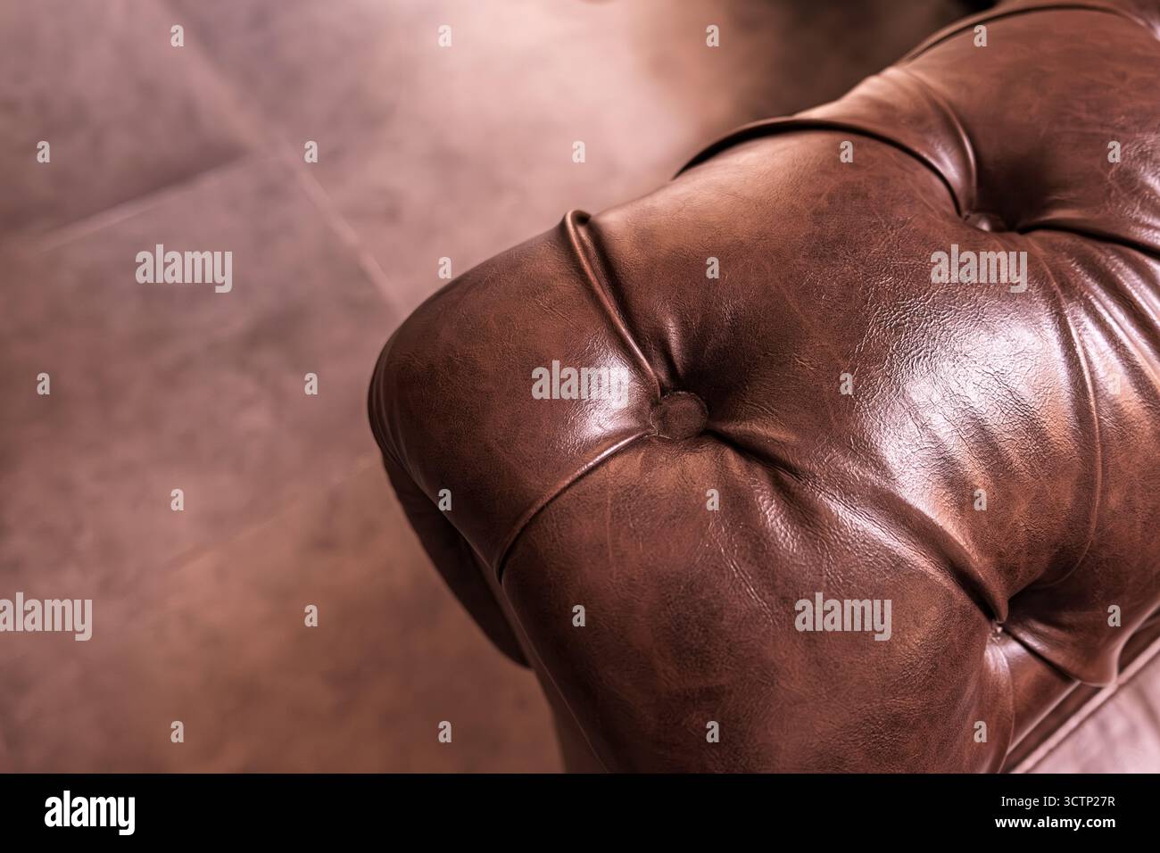 Nahaufnahme der braunen Lederarmlehne chesterfield. Die natürlichen Falten, die die Qualität und den Luxus des klassischen Innenmöbeldesigns demonstrieren. Se Stockfoto