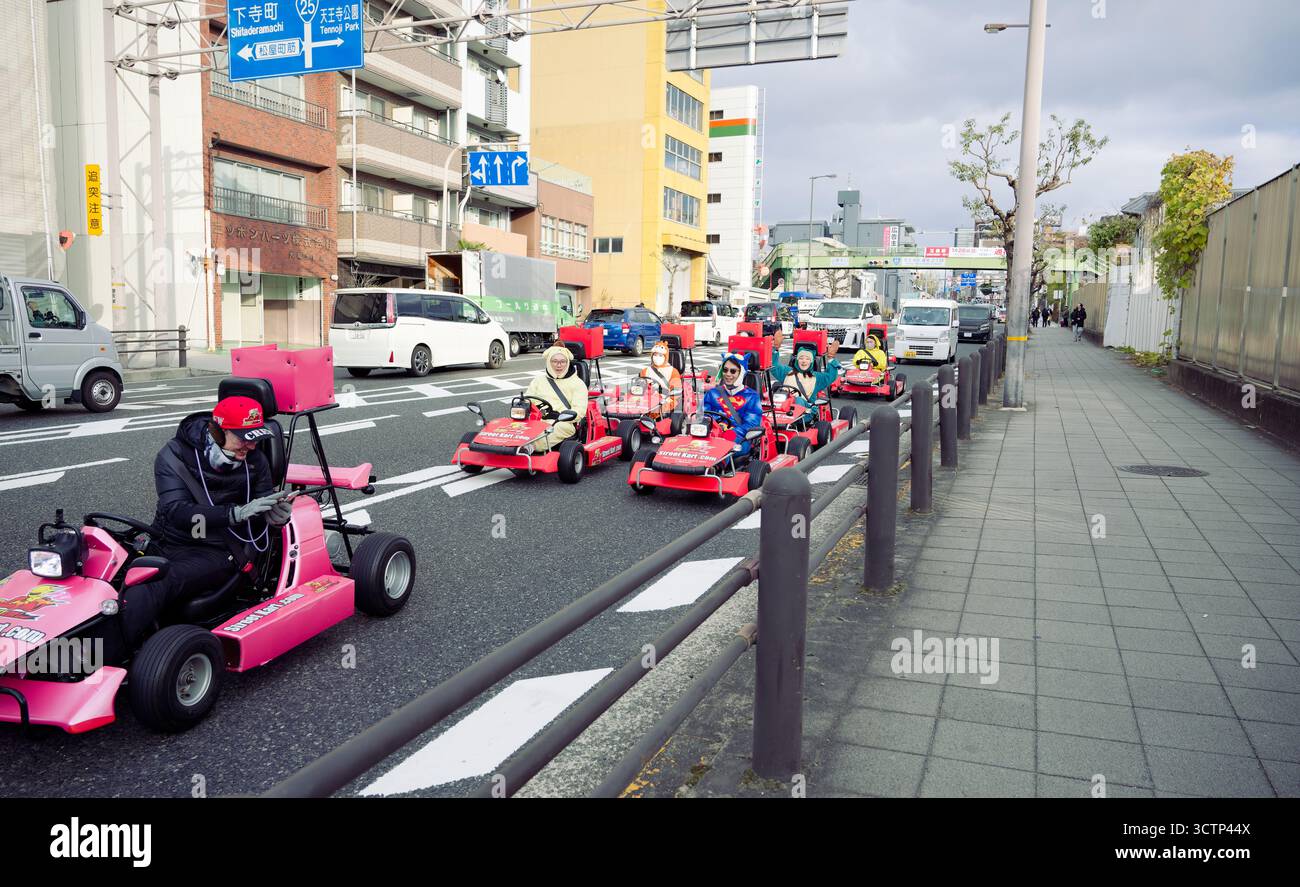 Gruppe von Menschen auf farbenfrohen Gokarts durch die geschäftigen Straßen von Osaka Stockfoto