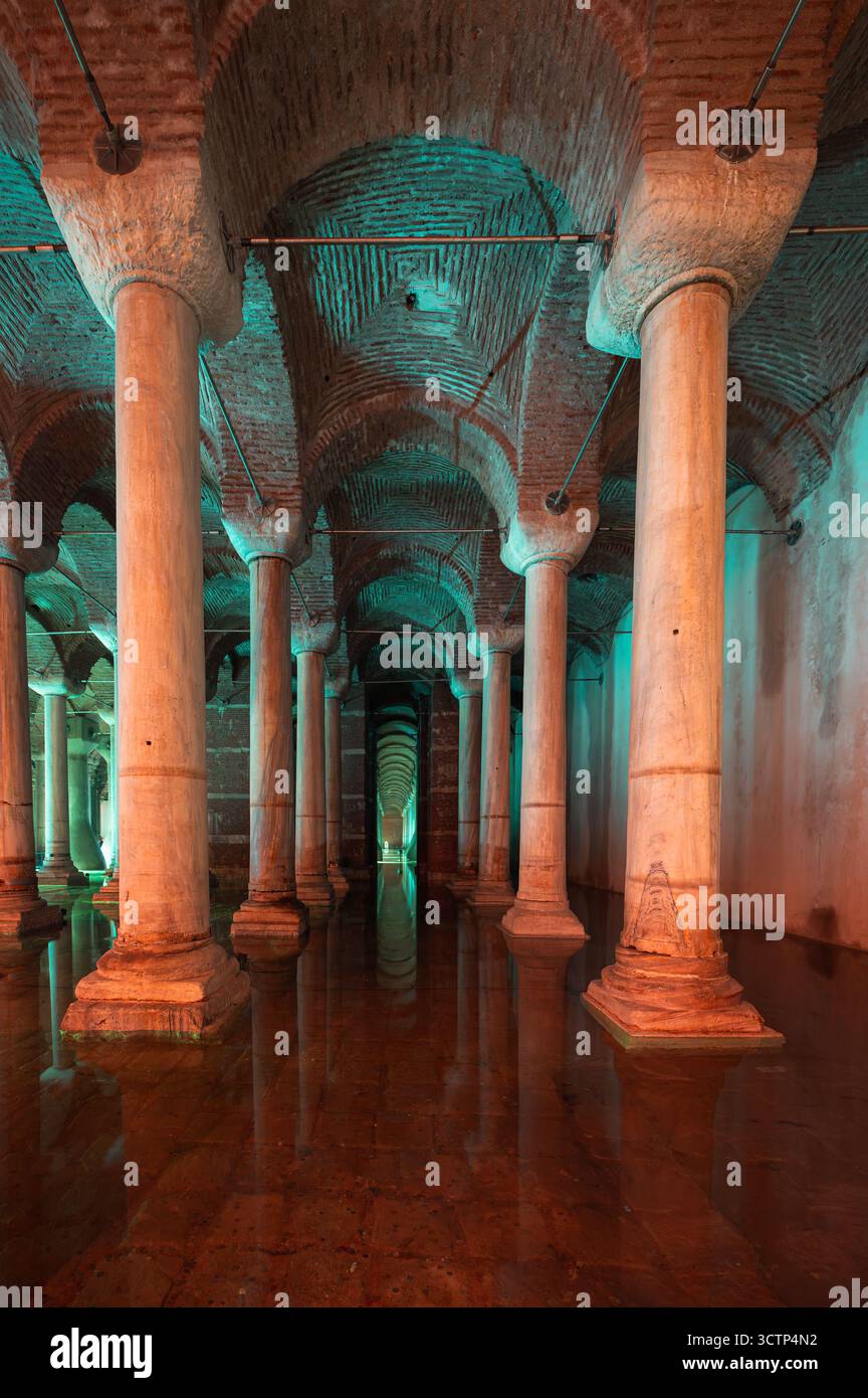 Die Zisterne der Basilika in Istanbul zeigt endlose Reihen von antiken Säulen, die sich in ruhigem Wasser spiegeln, und schafft so eine geheimnisvolle unterirdische Szene. Stockfoto