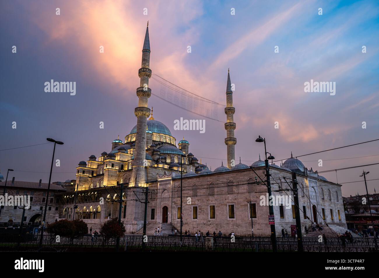 Die neue Moschee (Yeni Cami) in Istanbul, Türkei, wunderschön beleuchtet in der Abenddämmerung unter einem rosafarbenen Himmel, mit Kuppeln und Minaretten, die das klassische Ott widerspiegeln Stockfoto
