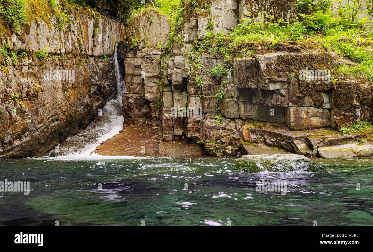 Wasserfall, der über felsige Klippen stürzt. Szene eines kleinen Wasserfalls, der über zerklüftete Felsen fließt. Fängt die ruhige Interaktion zwischen Wasser ein Stockfoto