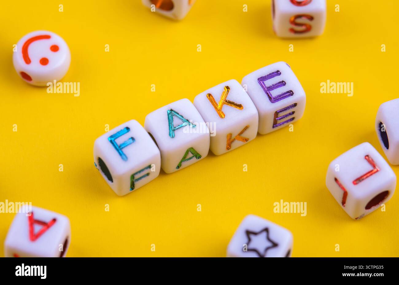 Wort gefälscht geschrieben mit bunten Buchstabenwürfeln auf gelbem Hintergrund. Darstellung falscher Informationen, Täuschung und irreführender Konzepte. Abstrakte Idee. Stockfoto