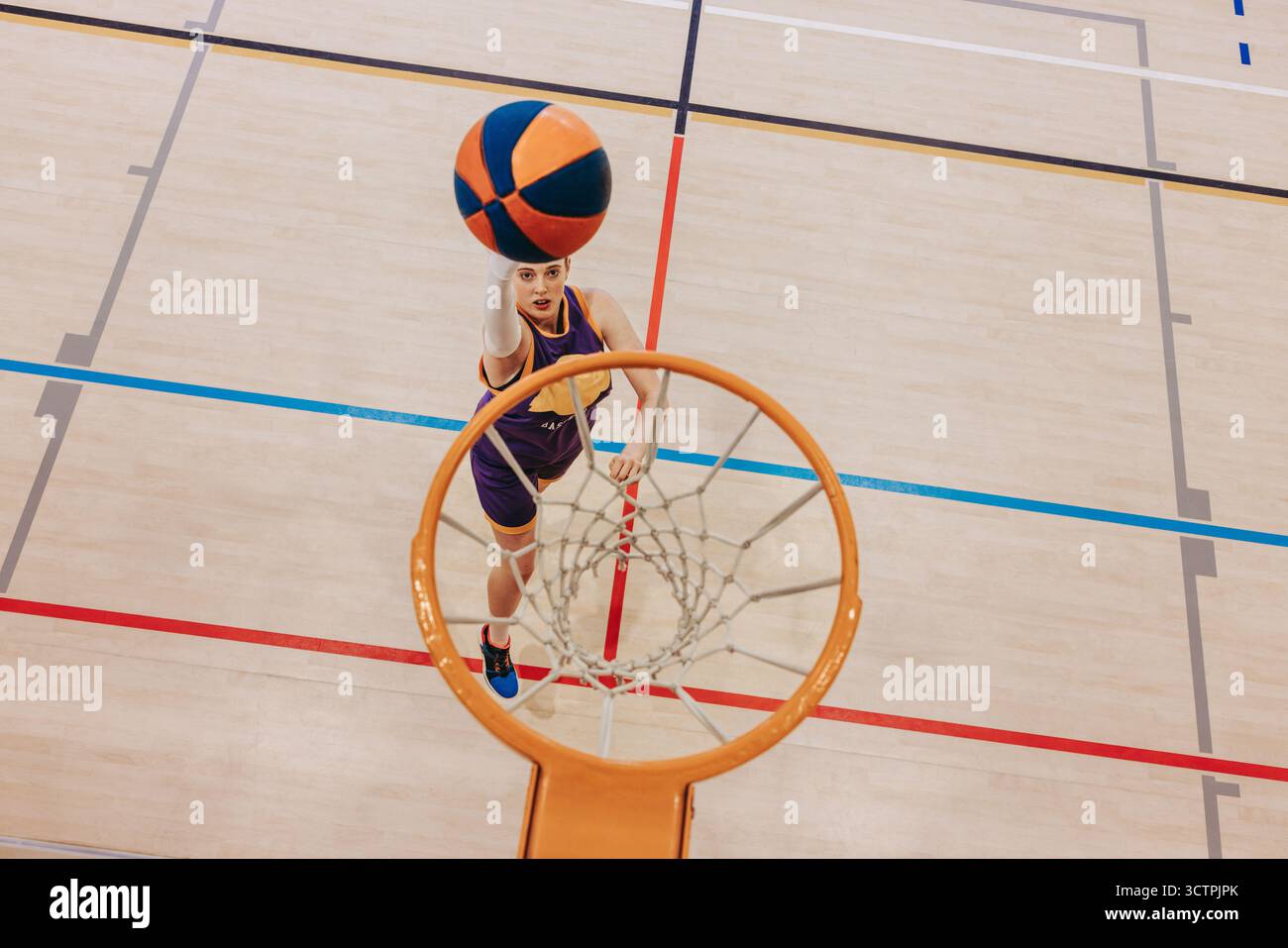 Ein dynamischer Blick von oben auf einen jungen Basketballspieler, der auf einem Hallenplatz einen Schuss erzielt. Der Spieler trägt Sportkleidung, zeigt Leichtathletik und Stockfoto