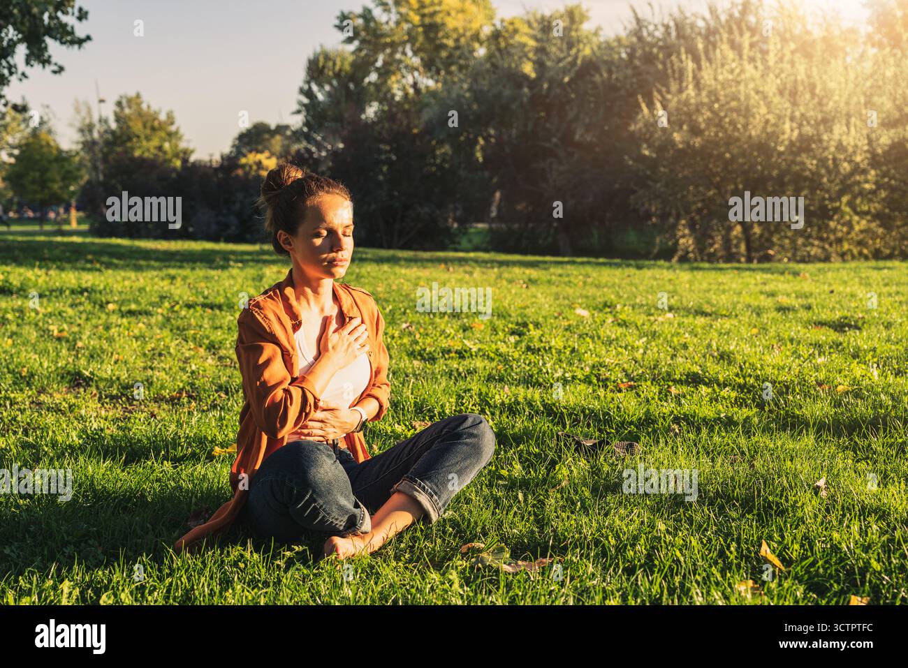 Frau meditiert nach der Arbeit in Lotusstellung im Stadtpark. Stockfoto