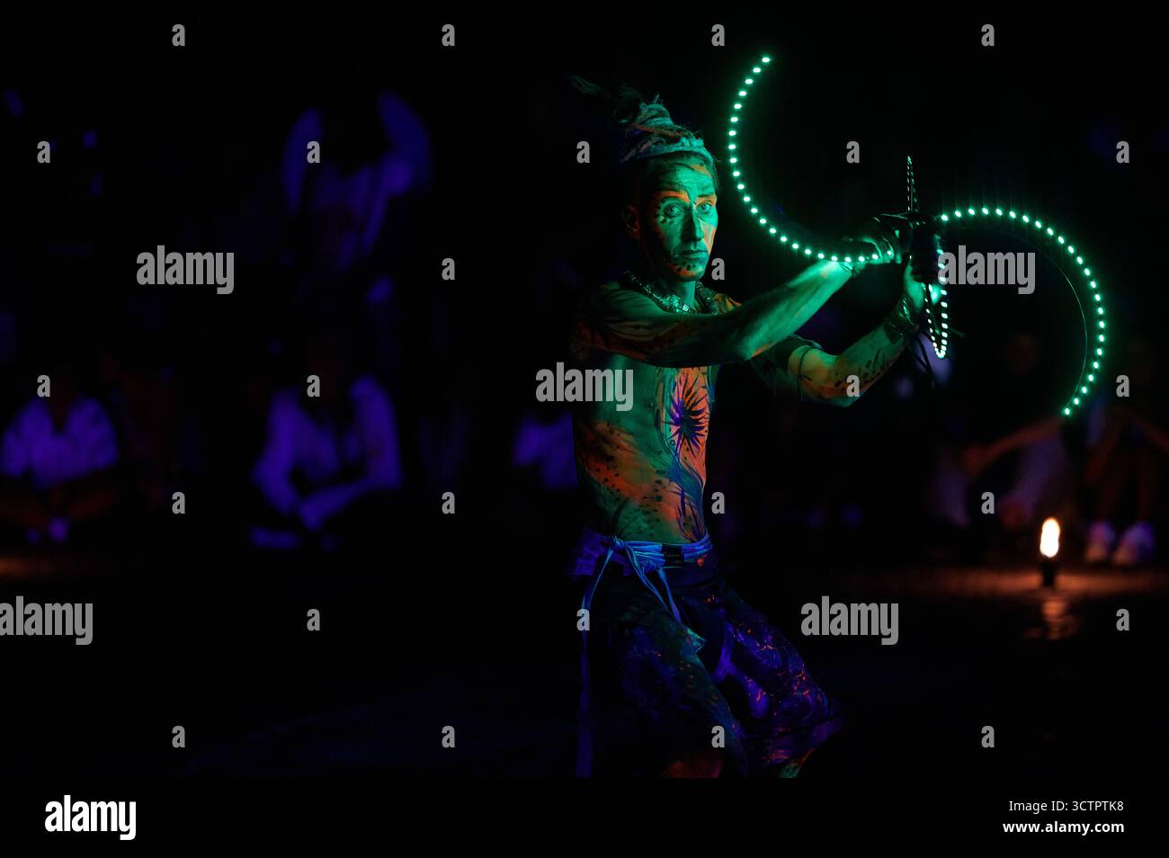 Feuertänzer dreht leuchtend grüne LED-Requisite während des Los Fuegos Fire Theatre in Polen, Nachtvorstellung mit künstlerischen Lichtspuren und dunklem Hintergrund, h Stockfoto