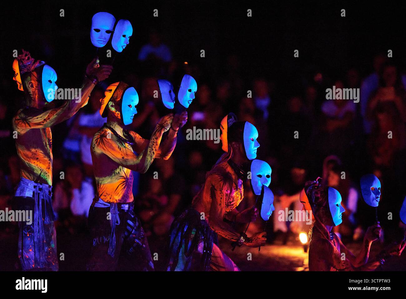 Maskierte Feuerdarsteller mit blau leuchtenden Gesichtern bewegen sich während des Los Fuegos Fire Theatre in Polen in Formation, die nachts mit intensiven Farben und Stron gedreht werden Stockfoto
