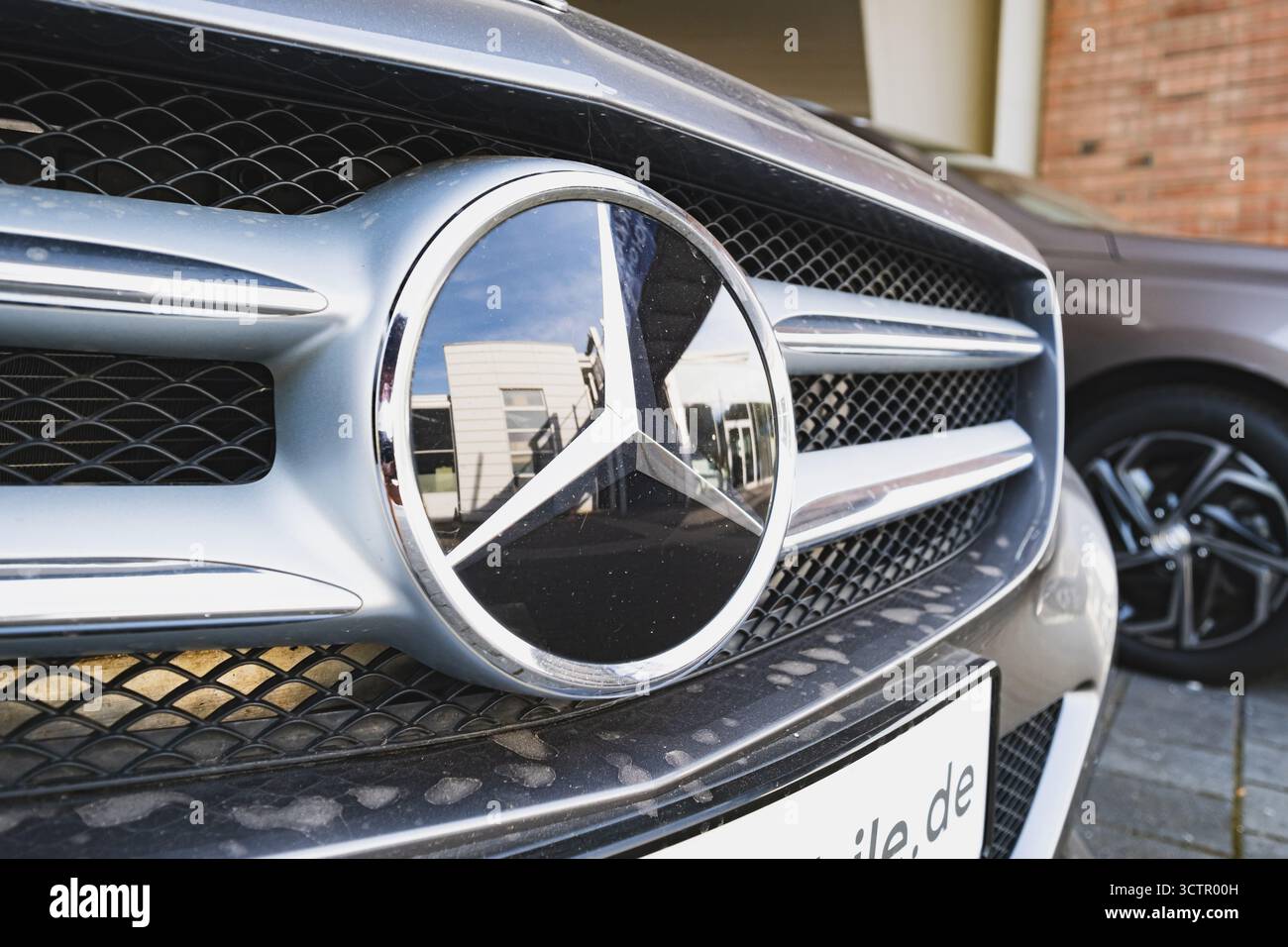 Mercedes-Benz Emblem auf der Vorderseite eines Fahrzeugs außerhalb des Händlerbetriebs Stockfoto