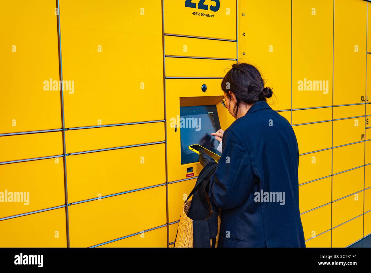 Person, die die DHL Self-Service-Paketstation im Freien nutzt Stockfoto