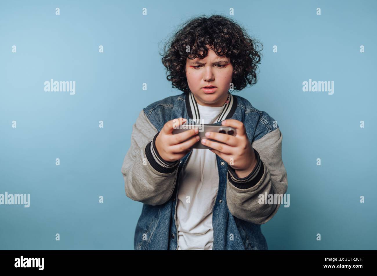 Teenager, die mobiles Spiel mit fokussiertem Ausdruck spielen Stockfoto