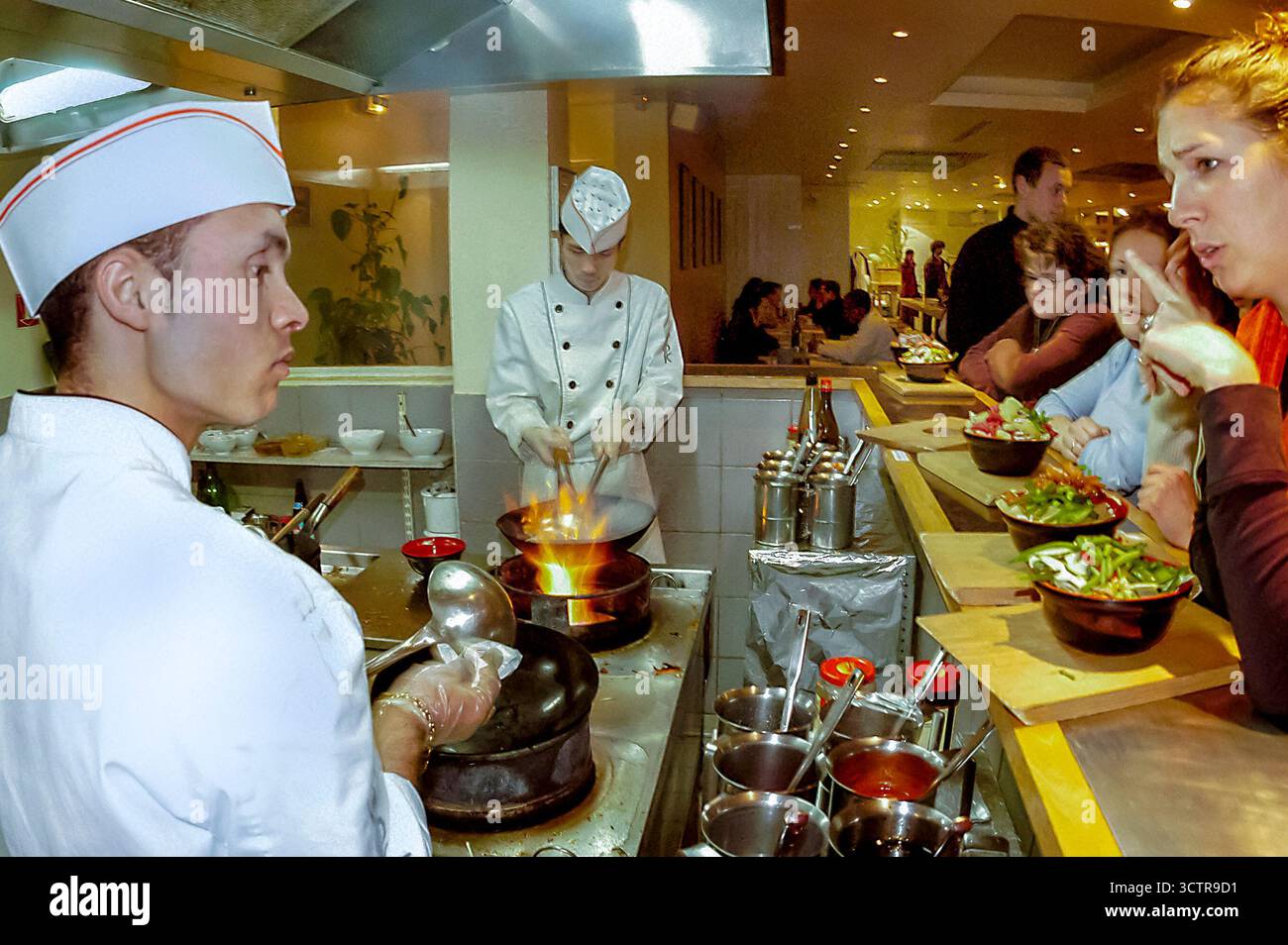 PARIS, Frankreich - männliche Köche bei der Arbeit in offener Küche, chinesisches Innenrestaurant, „Wok“, Theke, im Gespräch mit der Kellnerin Stockfoto