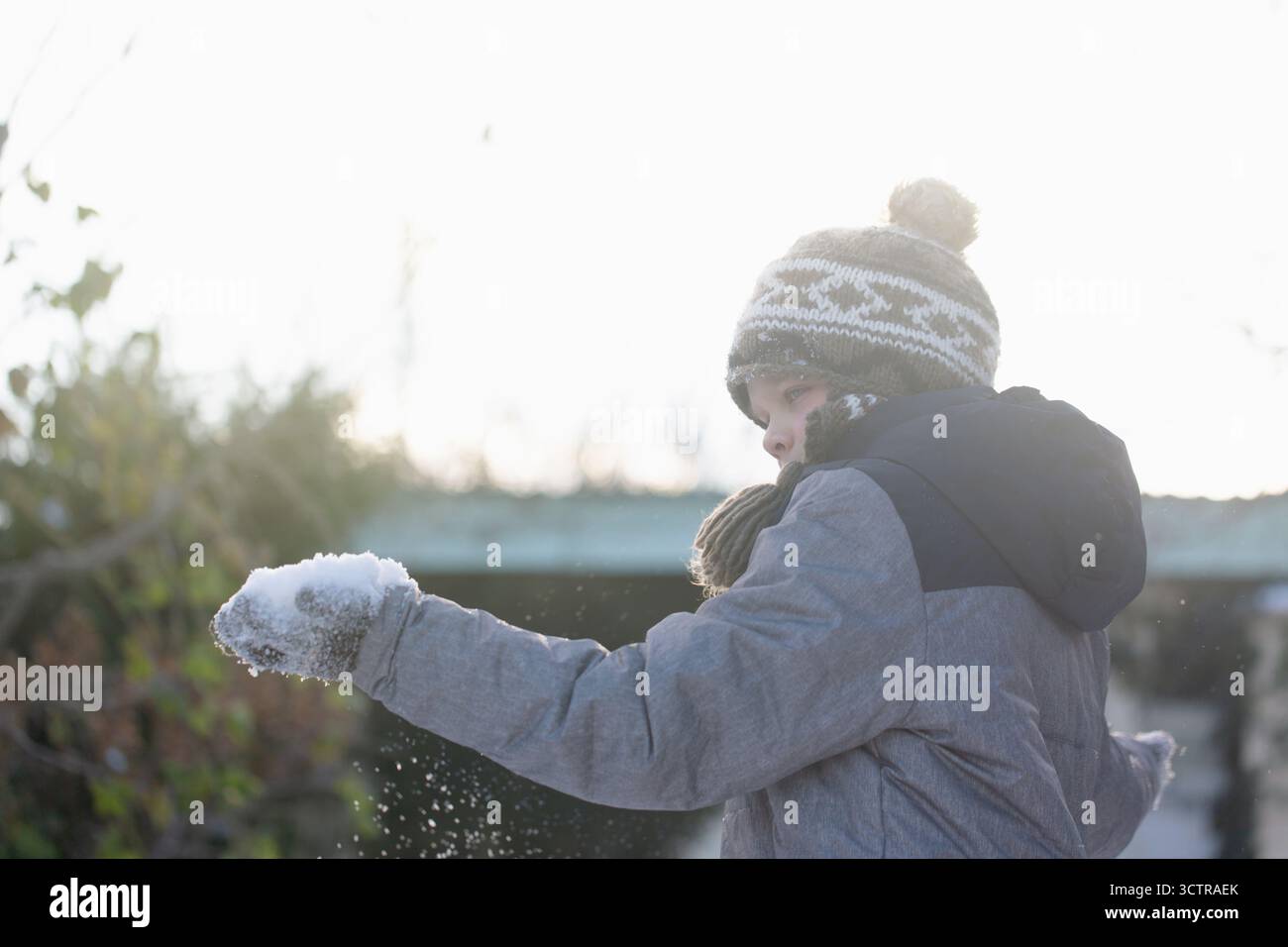Achtsames Kind steht an schneebedeckten Tagen draußen und beobachtet Schnee in der Hand, Symbol für Bewusstsein, Neugier und ruhige Verbindung mit der Natur Stockfoto