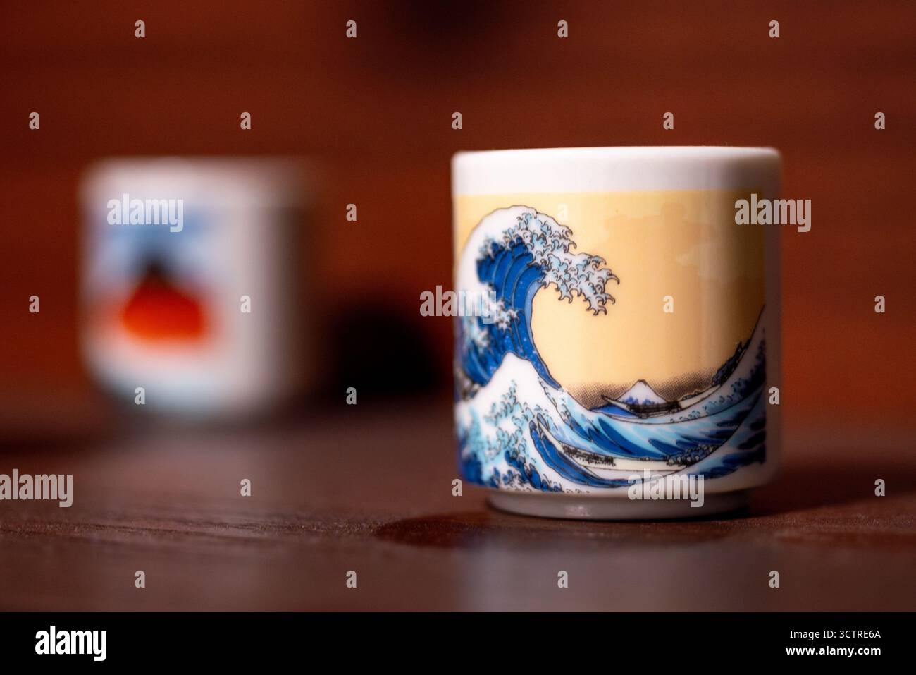 Keramikbecher mit Wellendesign, inspiriert von japanischer Kunst, auf Holzoberfläche. Stockfoto
