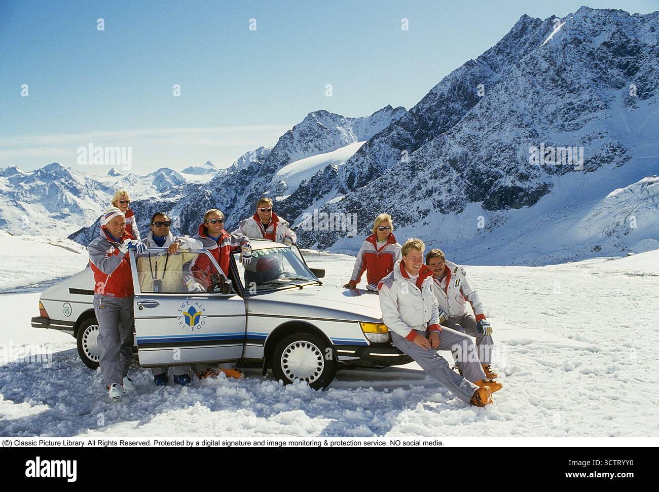 Saab 900. Das schwedische Alpinski-Team während eines Trainingslagers in den Alpen, Mai 1985. Einer der Sponsoren des Teams, der schwedische Automobilhersteller Saab, nutzte die Gelegenheit, sein Auto neben den Skifahrern fotografieren zu lassen. Ein Fotograf und Assistent haben die Athleten und die Saab 900 an einem hellen, sonnigen Tag mit den schneebedeckten Alpen als Kulisse arrangiert. Der Saab 900 wurde erstmals im Herbst 1978 als Modelljahr 1979 eingeführt. Entwickelt aus der beliebten Saab 99, wurde es in zeitgenössischen Automobilzeitschriften als „Aufstieg in die Luxusklasse“ beschrieben. Das Modell wurde Saabs erfolgreichste Modell Stockfoto