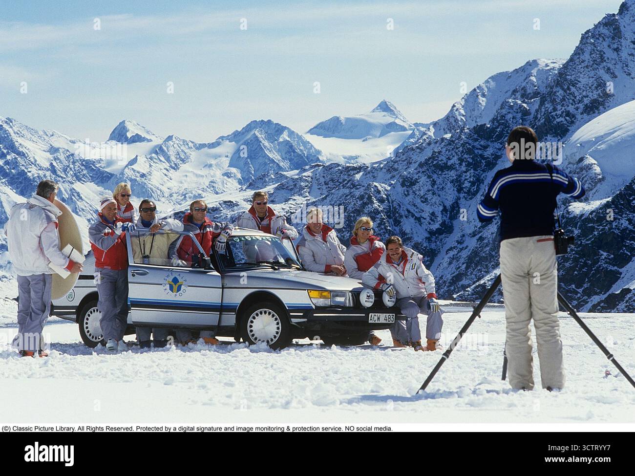 Saab 900. Das schwedische Alpinski-Team während eines Trainingslagers in den Alpen, Mai 1985. Einer der Sponsoren des Teams, der schwedische Automobilhersteller Saab, nutzte die Gelegenheit, sein Auto neben den Skifahrern fotografieren zu lassen. Ein Fotograf und Assistent haben die Athleten und die Saab 900 an einem hellen, sonnigen Tag mit den schneebedeckten Alpen als Kulisse arrangiert. Der Saab 900 wurde erstmals im Herbst 1978 als Modelljahr 1979 eingeführt. Entwickelt aus der beliebten Saab 99, wurde es in zeitgenössischen Automobilzeitschriften als „Aufstieg in die Luxusklasse“ beschrieben. Das Modell wurde Saabs erfolgreichste Modell Stockfoto