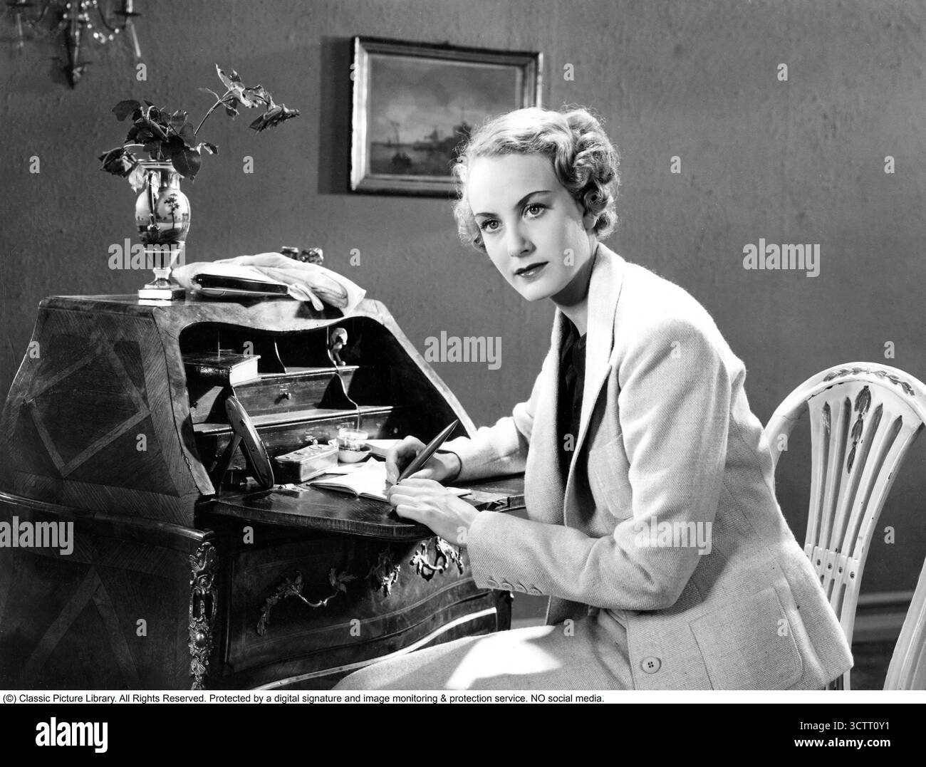 Anne-Marie Brunius (1916–2002), eine schwedische Schauspielerin, sitzt in den 1930er Jahren an ihrem eleganten Schreibtisch und ist in ihrem Notizbuch vertieft. Anne-Marie Brunius, Tochter des berühmten Dramatikers August Brunius, war in den 1930er Jahren ein aufstrebender Star im schwedischen Theater und Film Bekannt für ihre Rollen in Filmen wie Flickorna på Uppåkra (1936), verkörperte sie die Raffinesse der Zeit und verschmolz intellektuelle Bestrebungen mit ihrem Talent für Theater. Stockfoto