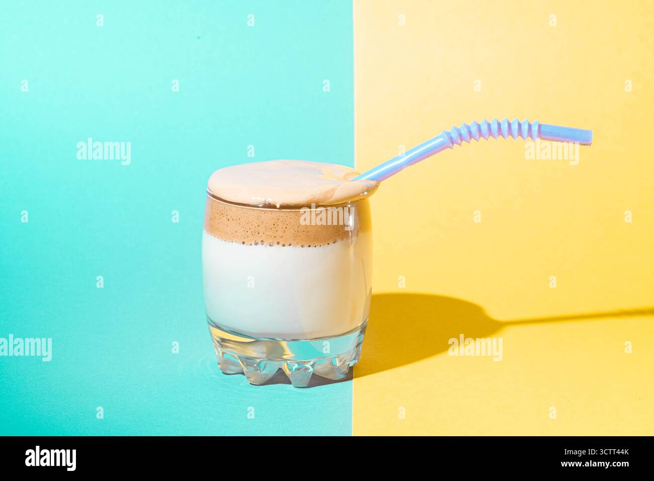 Dalgona-Kaffee mit üppigem Schaum in einem Glas auf gelbem und blauem Hintergrund. Trendiges Koreanisches Getränk. Stockfoto