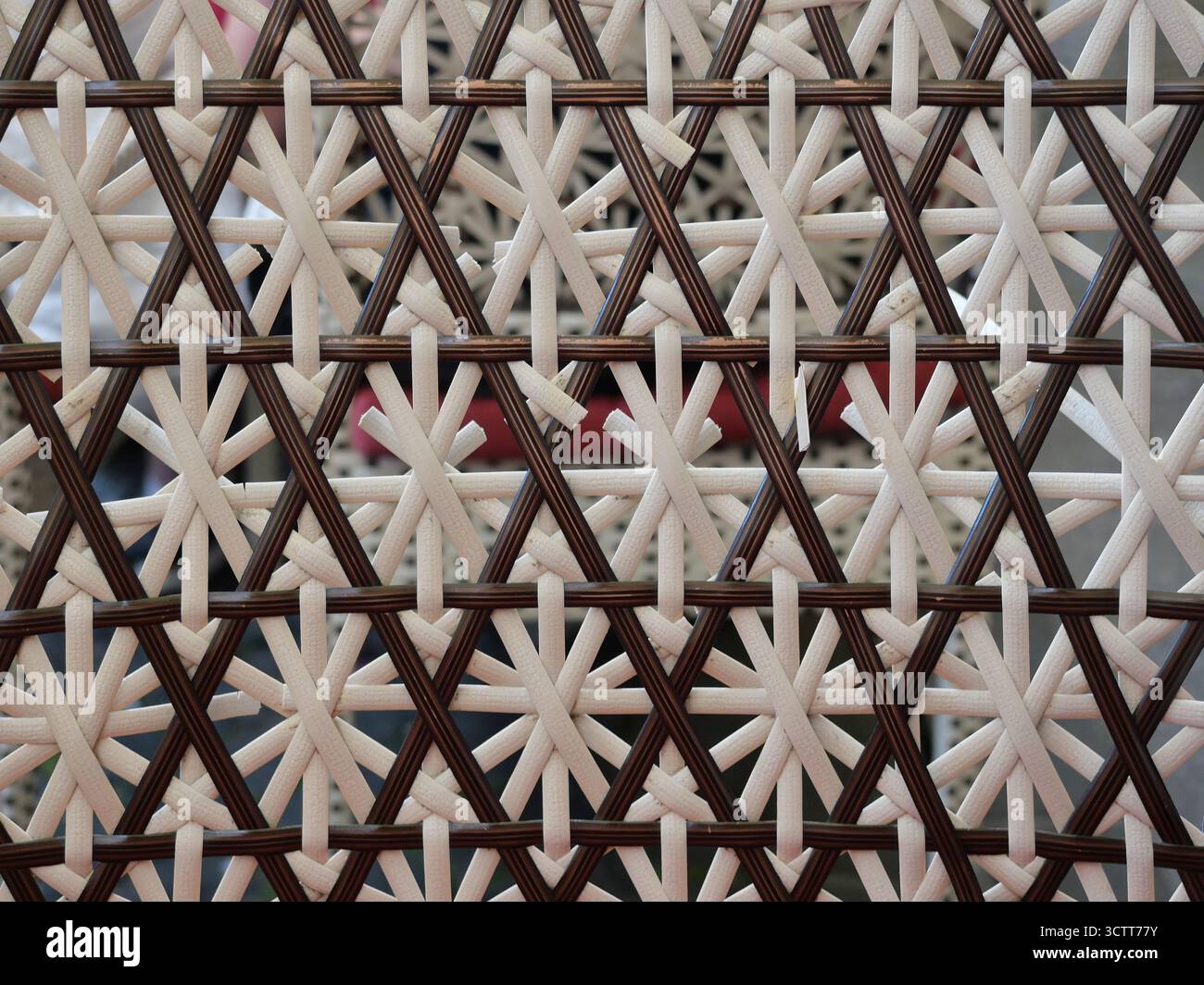 Rattan aus Sternengewebe mit dunkelbraunen und cremefarbenen Fäden in Kontrastmuster. Nahaufnahme. Kopierraum. Stockfoto