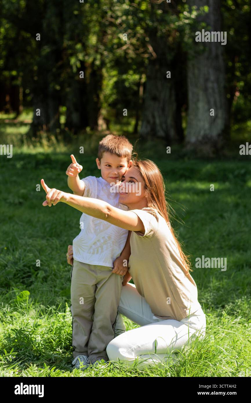 Der neugierige Junge und seine Mutter knien neben ihm. Moment der gemeinsamen Entdeckung und des Lernens in Waldlandschaften. Ideal für Bildungs- und Familienverbände Stockfoto