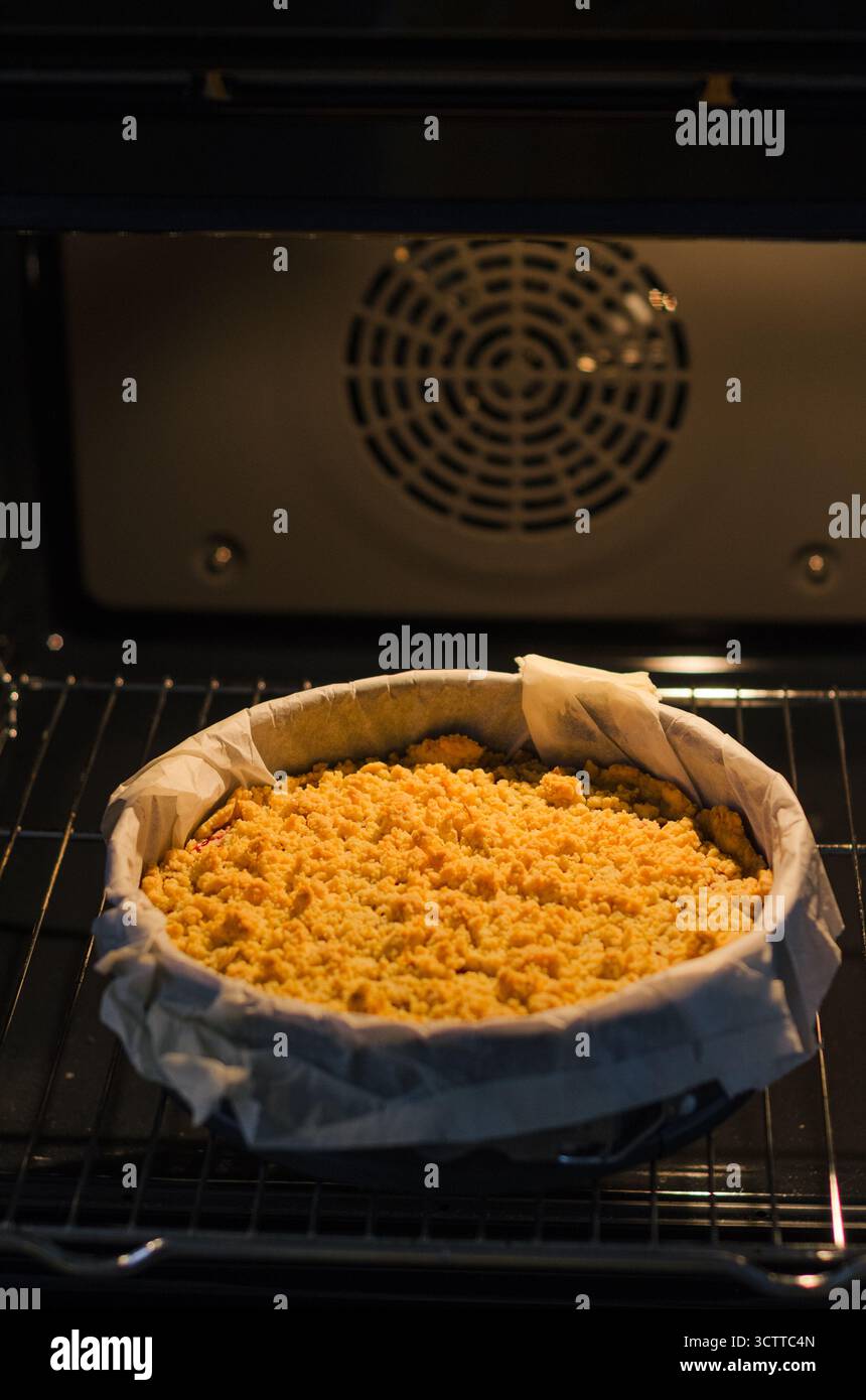 Hausgemachte Sbriciolata Crumble Pie mit Marmelade im Ofen in einer Springform. Garniert mit goldenen Butterbröseln. Gemütliches Herbst- und Winterdessert. Stockfoto