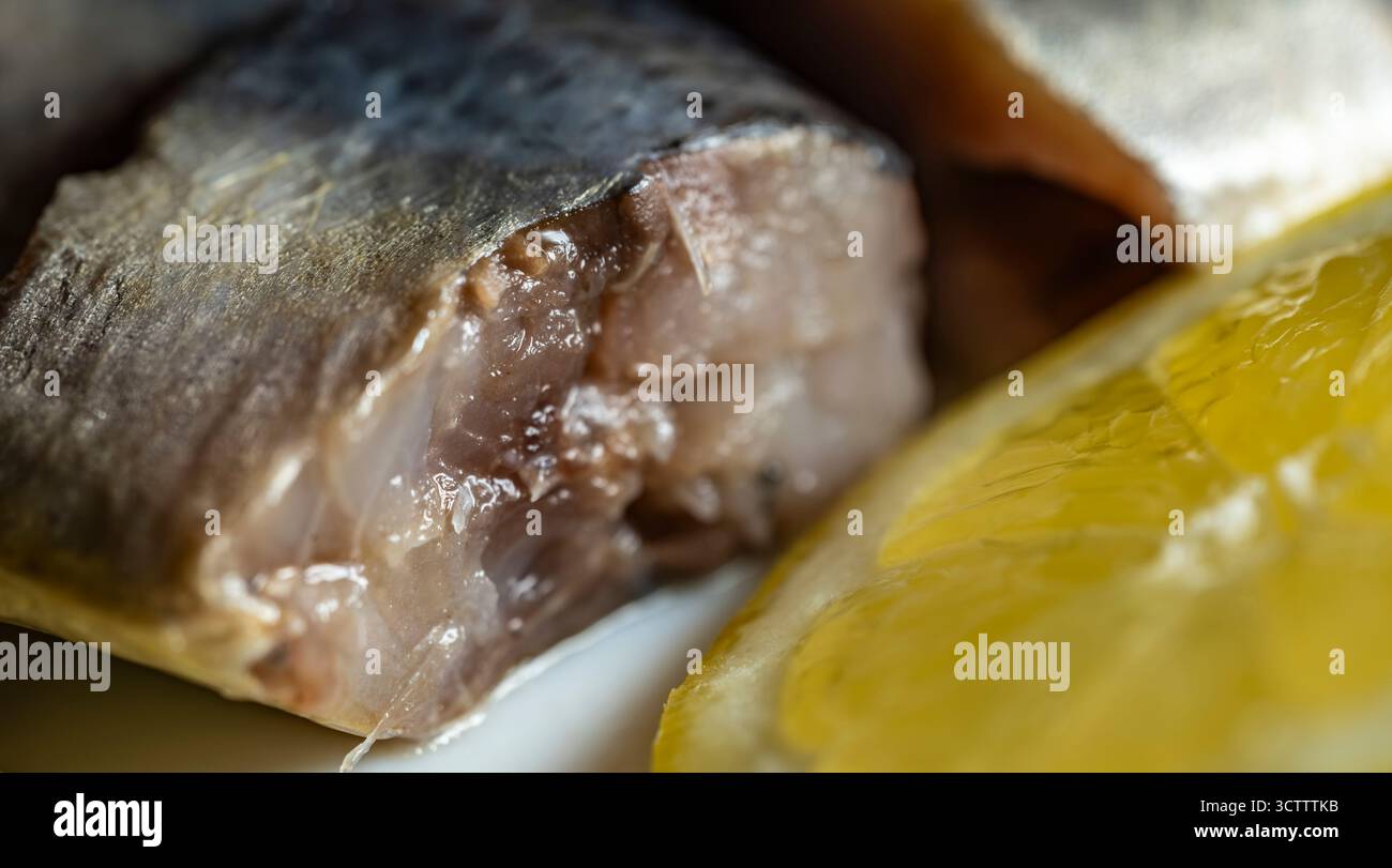 Pazifischer Hering in Scheiben auf weißem Teller mit Zitronensaft, Zwiebelringen und Zitronenscheiben, Meeresfrüchtegericht in Nahaufnahme Stockfoto