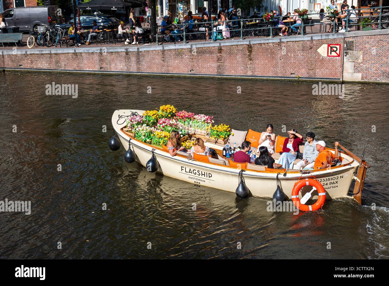 Amsterdam, Niederlande, 29. August 2025. Menschen an Bord des Flagship-Kanalbootes, dekoriert mit bunten Blumentöpfen. Top-Down, Weitwinkelüberblick Stockfoto