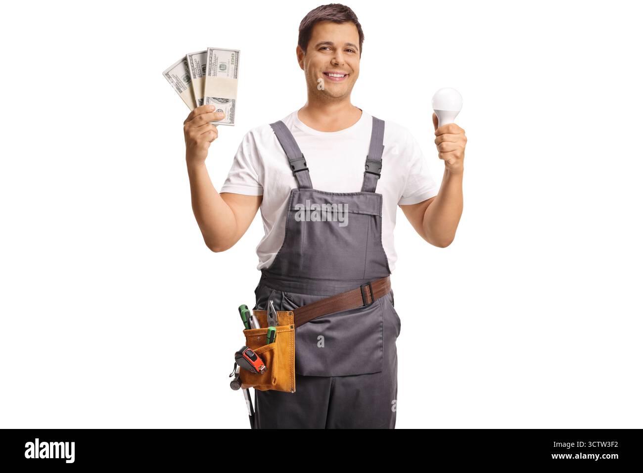 Ein Reparaturmann hält eine energieeffiziente Glühbirne und Geldstapel isoliert auf weißem Hintergrund Stockfoto