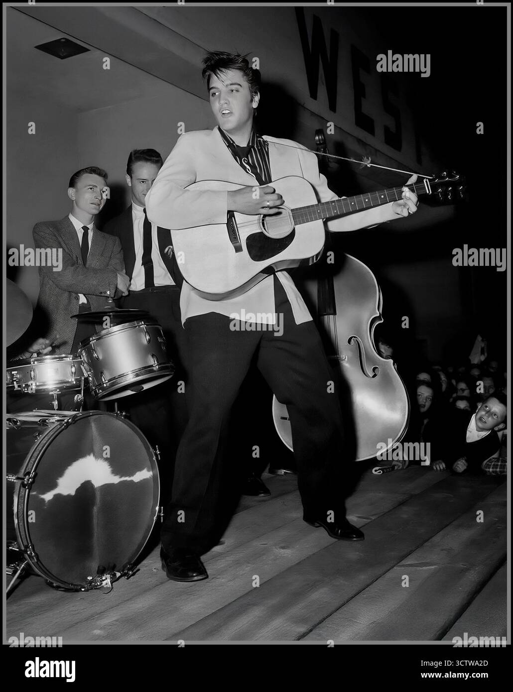 Elvis Presley trat 1956 mit seiner Band The Blue Moon Boys auf. Das Foto wurde 1956 aufgenommen, einem entscheidenden Jahr für Presleys Karriere, als er sein Debütalbum veröffentlichte und seine erste Nummer-Eins-Single Heartbreak Hotel hatte. Die im Bild sichtbaren Bandmitglieder sind Elvis Presley an der Gitarre, D.J. Fontana am Schlagzeug und Bill Black am Stand-up Bass. Stockfoto
