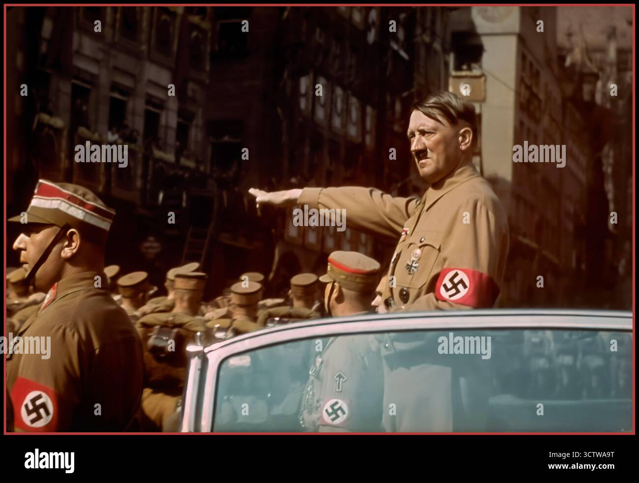 Adolf Hitler salutiert SA Sturmabteilung Truppen Vintage Nazi Deutschland um 1935. Nürnberger Rallye, farbige Fotokarte von Adolf Hitler mit Hakenkreuzarmband in offenen Mercedes- und SA-Truppen, die mit Hakenkreuzfahnen vorbeimarschieren, Verlag H. Wiedemann, Sturmabteilung die offizielle Uniform der SA war das braune Hemd mit brauner Krawatte, bekannt als „die braunen Shirts“. Stockfoto