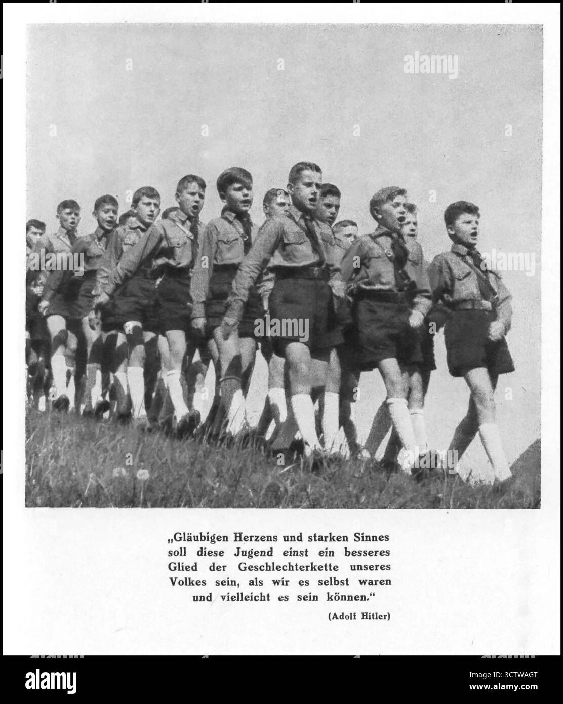 Hitlerjugend in Uniform marschieren und singen, 1930er Jahre Adolf Hitler zitiert: „Mit gläubigem Herzen und starkem Verstand wird diese Jugend eines Tages ein besseres Glied in der Kette der Generationen unseres Volkes sein, als wir selbst waren und vielleicht sein können.“ Stockfoto