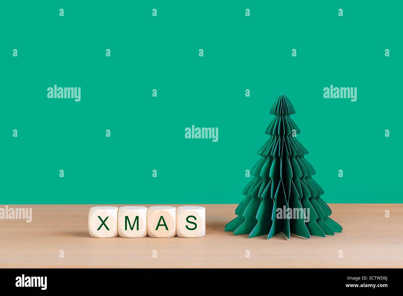 WEIHNACHTSWÜRFEL und grüner Papierbaum auf Holzplatte Stockfoto
