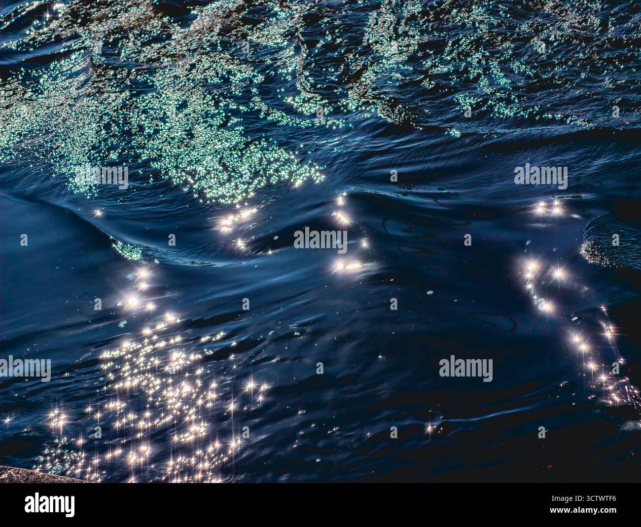 Funkelnde Ozeanwelle mit Sonnenlichtreflektionen - tiefblaue Meerwasser-Oberflächenstruktur für Natur- und Meditationshintergrund-Design. Natürliches Hintergrundbild Stockfoto