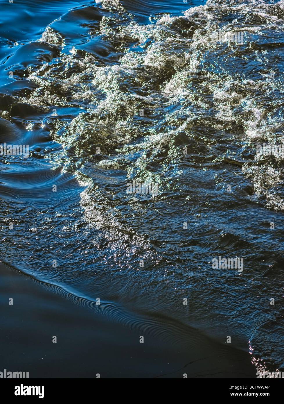 Glitzernde Ozeanwasseroberfläche mit Sonnenlichtreflektionen - abstrakte blaue Meereswellen-Textur für Natur und Meditationsinhalte. Natürlicher Hintergrund Stockfoto