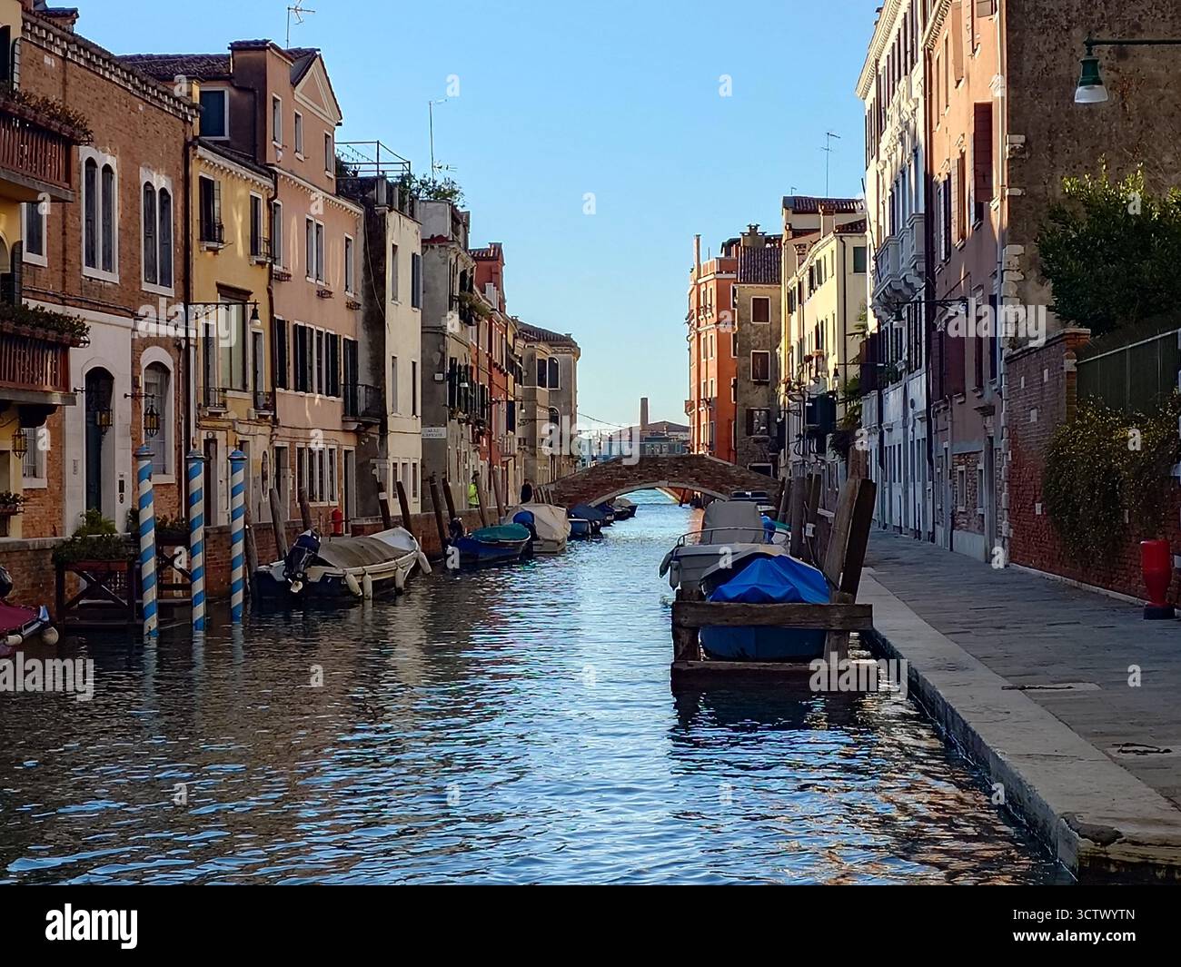Ein Kanal in Venedig, Italien. Häuser entlang des Kanals, Boote, die an den Häusern verankert sind Stockfoto