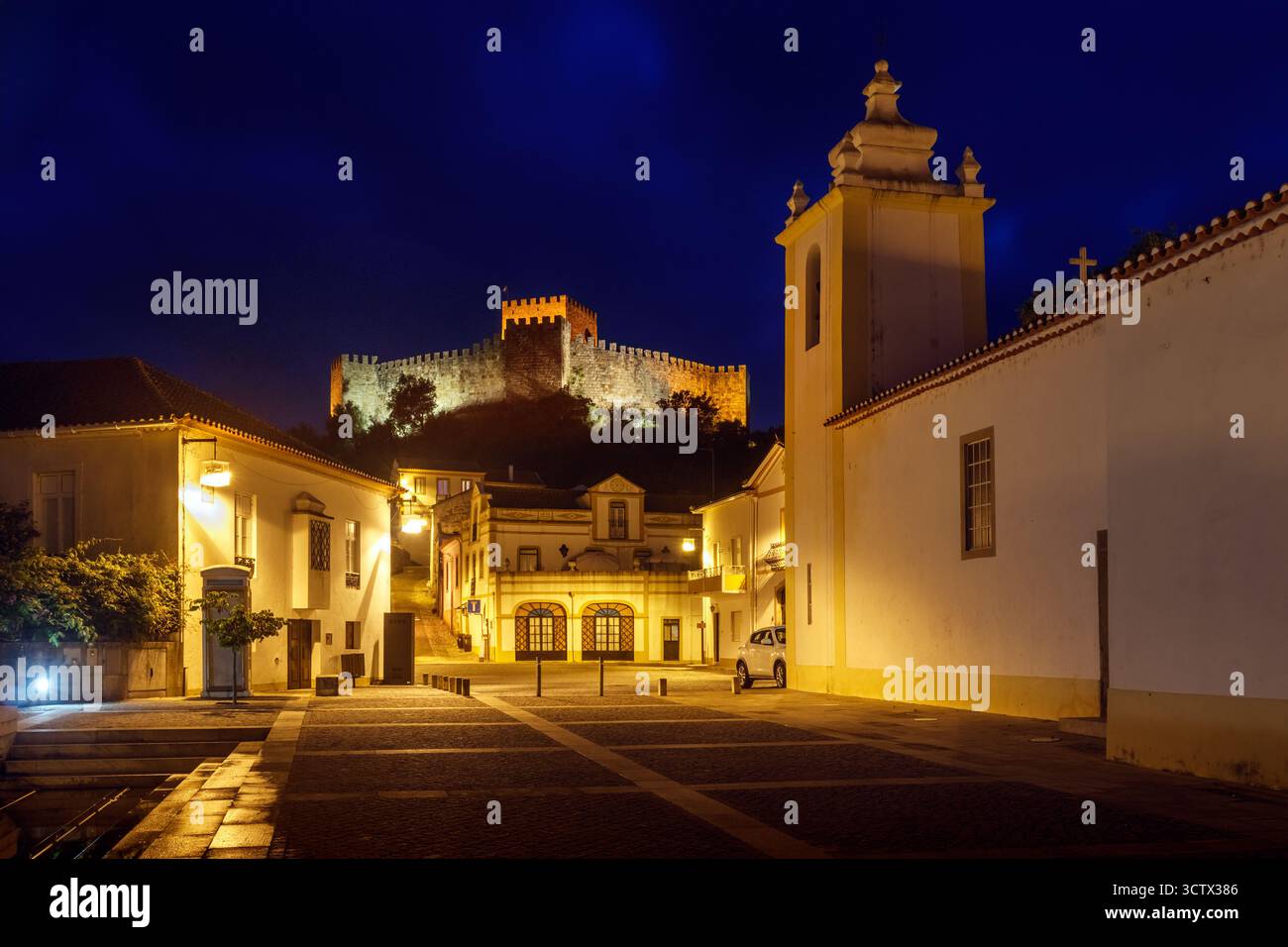 Blick auf das Zentrum des Dorfes Belver, Portugal, in der Abenddämmerung, mit den Lichtern an und dem Schloss, das oben beleuchtet ist Stockfoto